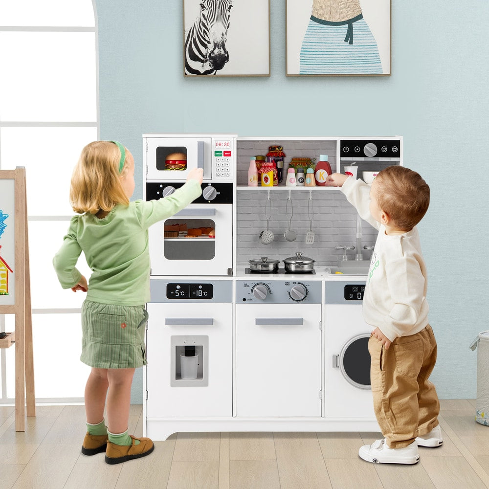 Two young children playing with the white play kitchen set
