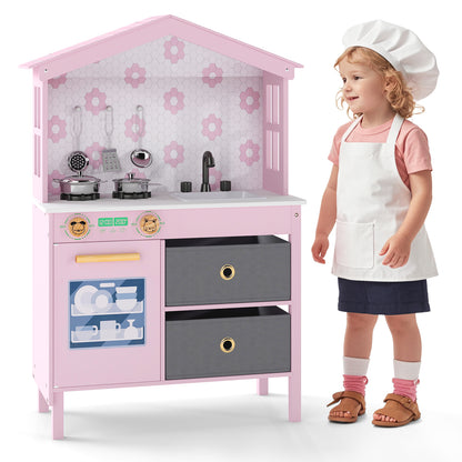Two children standing next to the pink play kitchen set, one wearing a chef hat