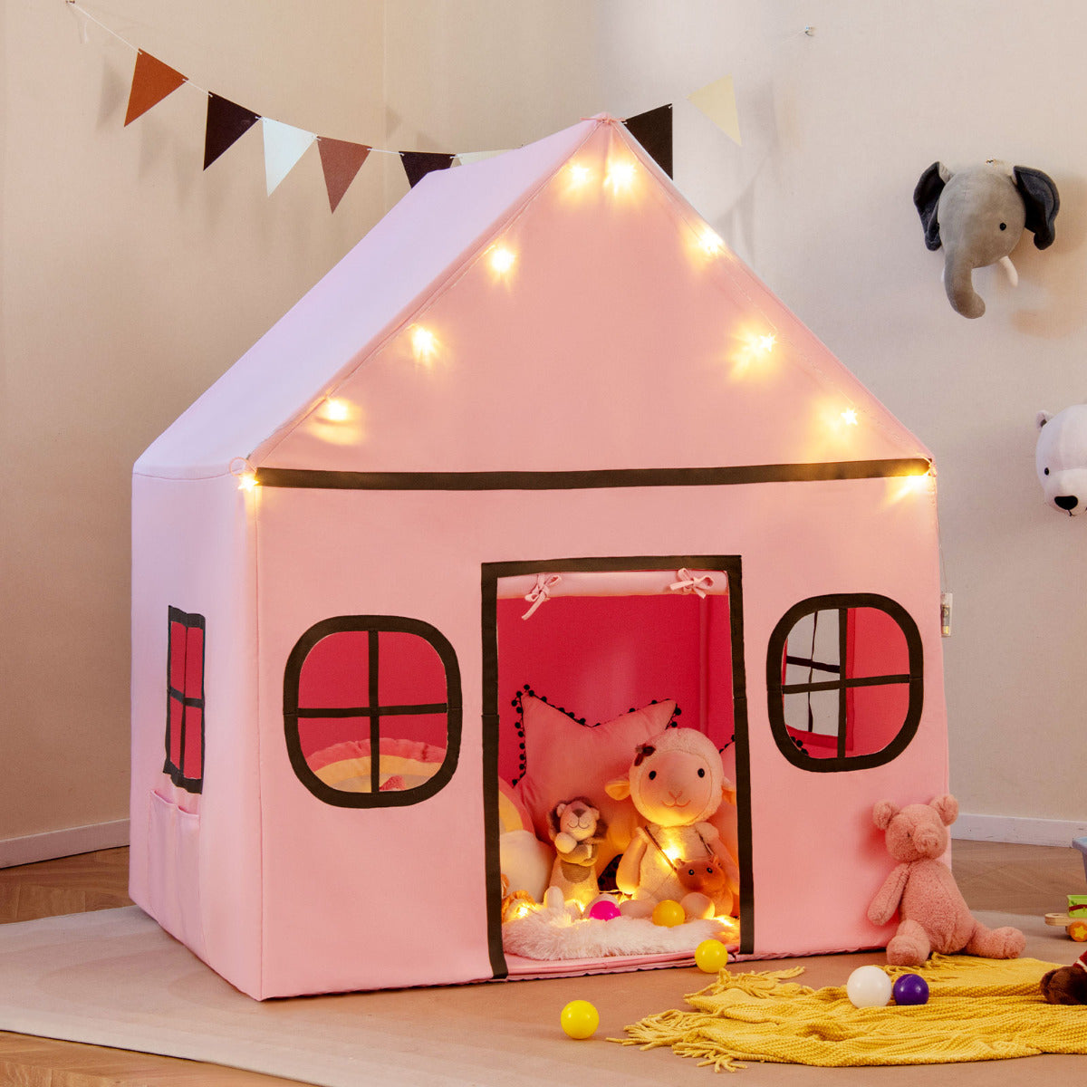 This pink playhouse is decorated with bunting and surrounded by toys