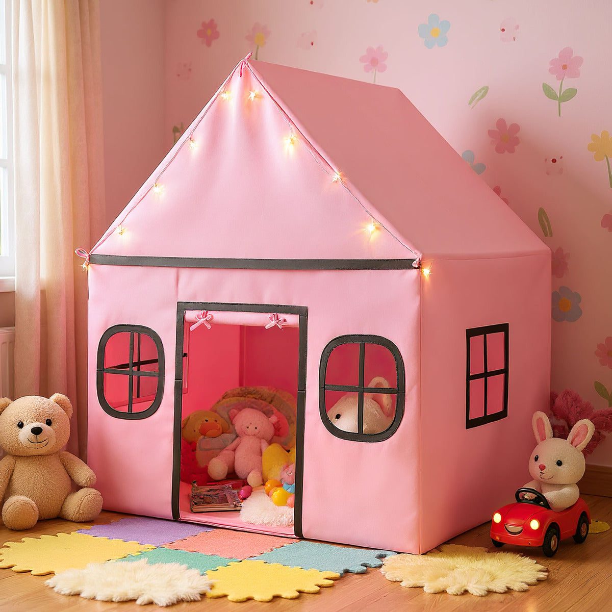 The large pink playhouse is set up indoors with toys and soft furnishings