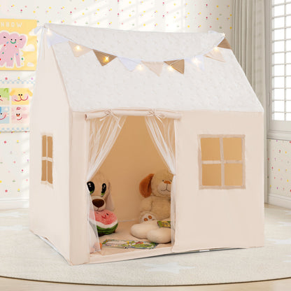 The kids play tent is a beige fabric house with a white door curtain and bunting on the roof