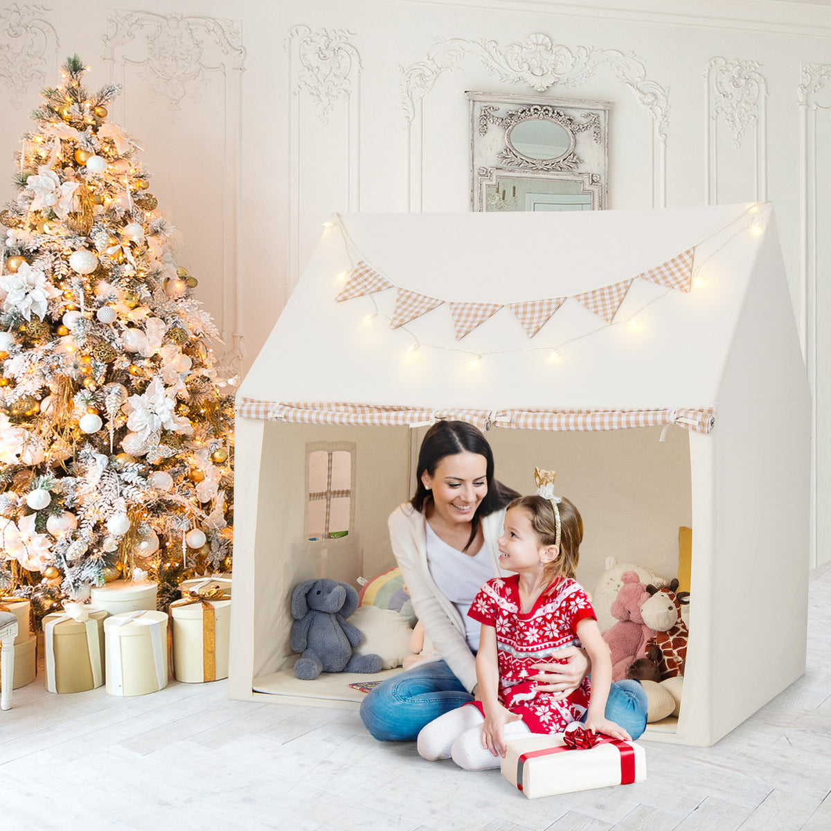The play tent set up in a room with a Christmas tree, with a mother and child sitting inside