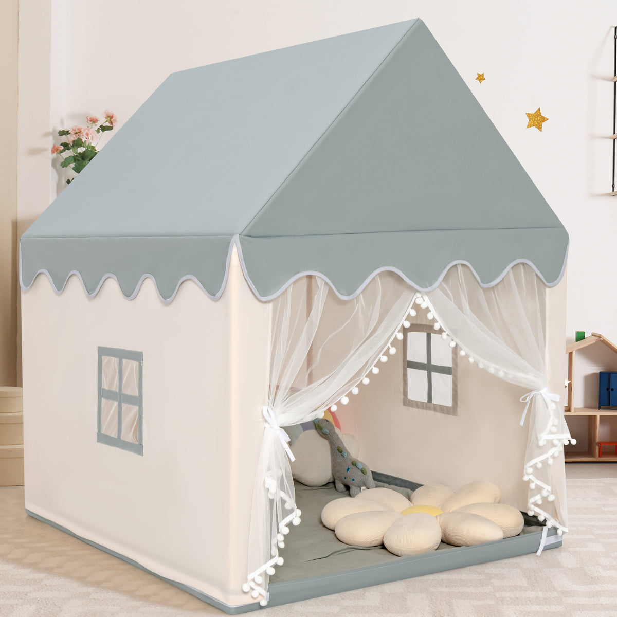 Beige and grey indoor playhouse for children, showing the entrance with lace curtains and decorative pompons