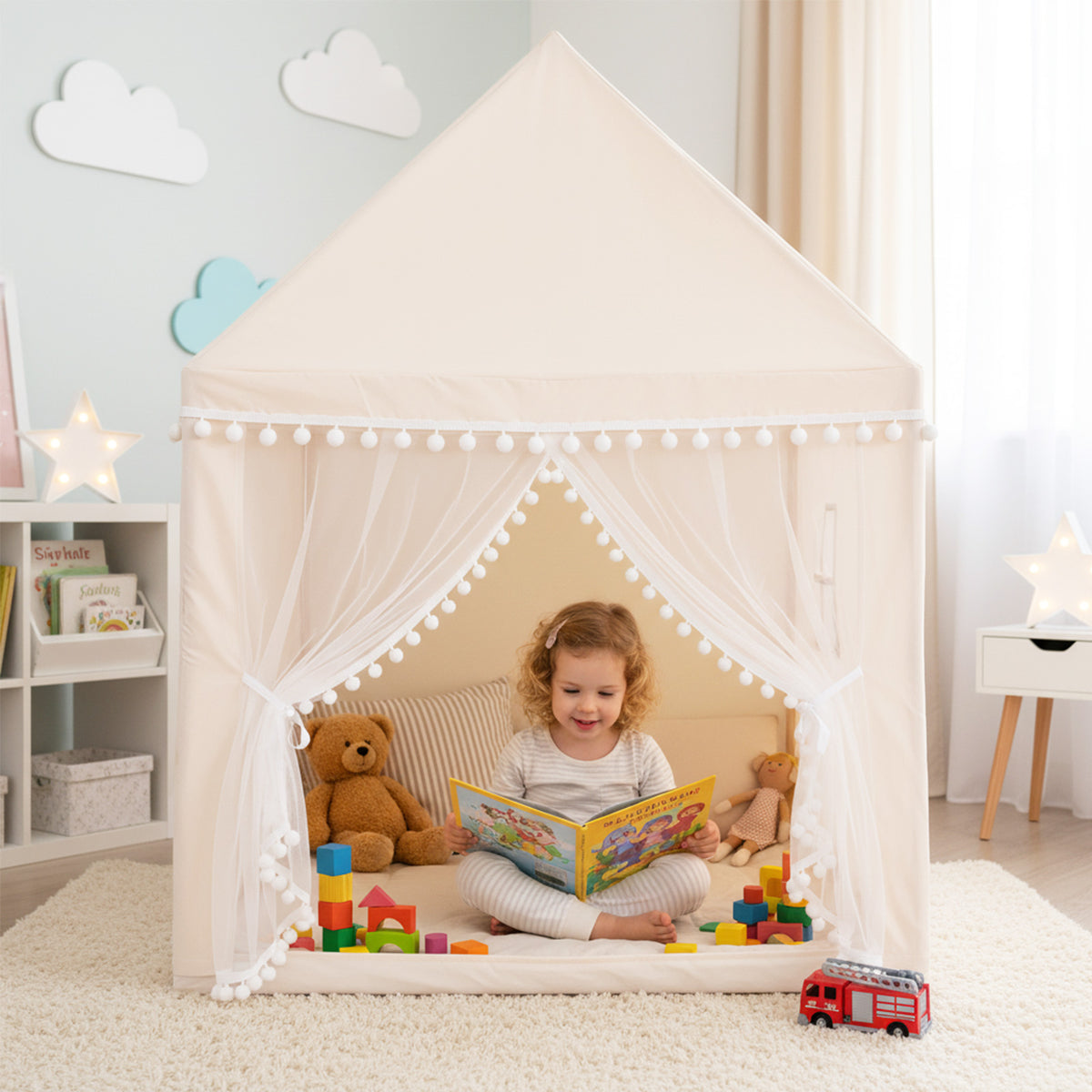 A young girl reading a book inside the play tent, surrounded by toys and a teddy bear