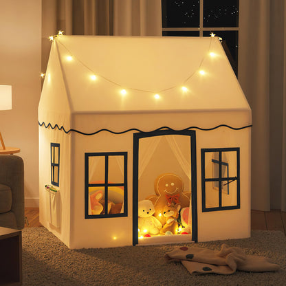 The beige play tent is lit up with fairy lights and filled with toys and stuffed animals