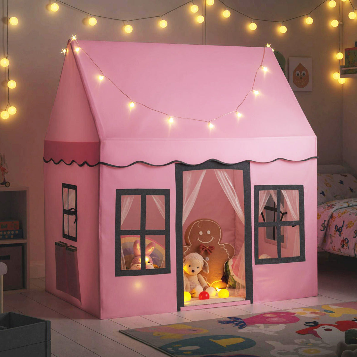 The play tent illuminated by warm star lights in a dimly lit room with a patterned rug