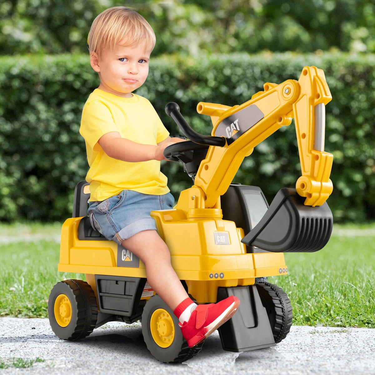 A young boy sitting on the yellow ride on toy in a garden setting