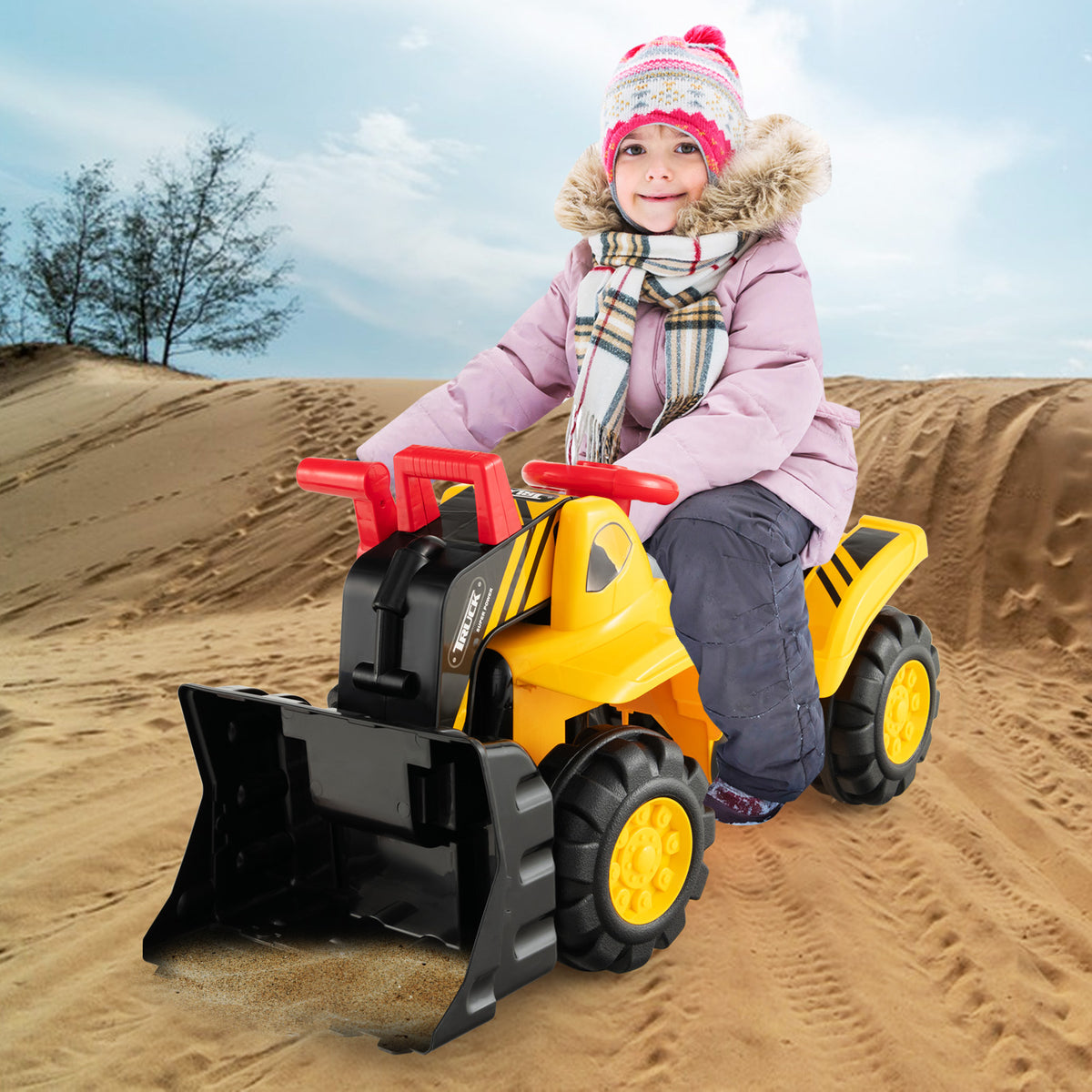 The ride on toy being used by a child in winter clothes on a sandy beach