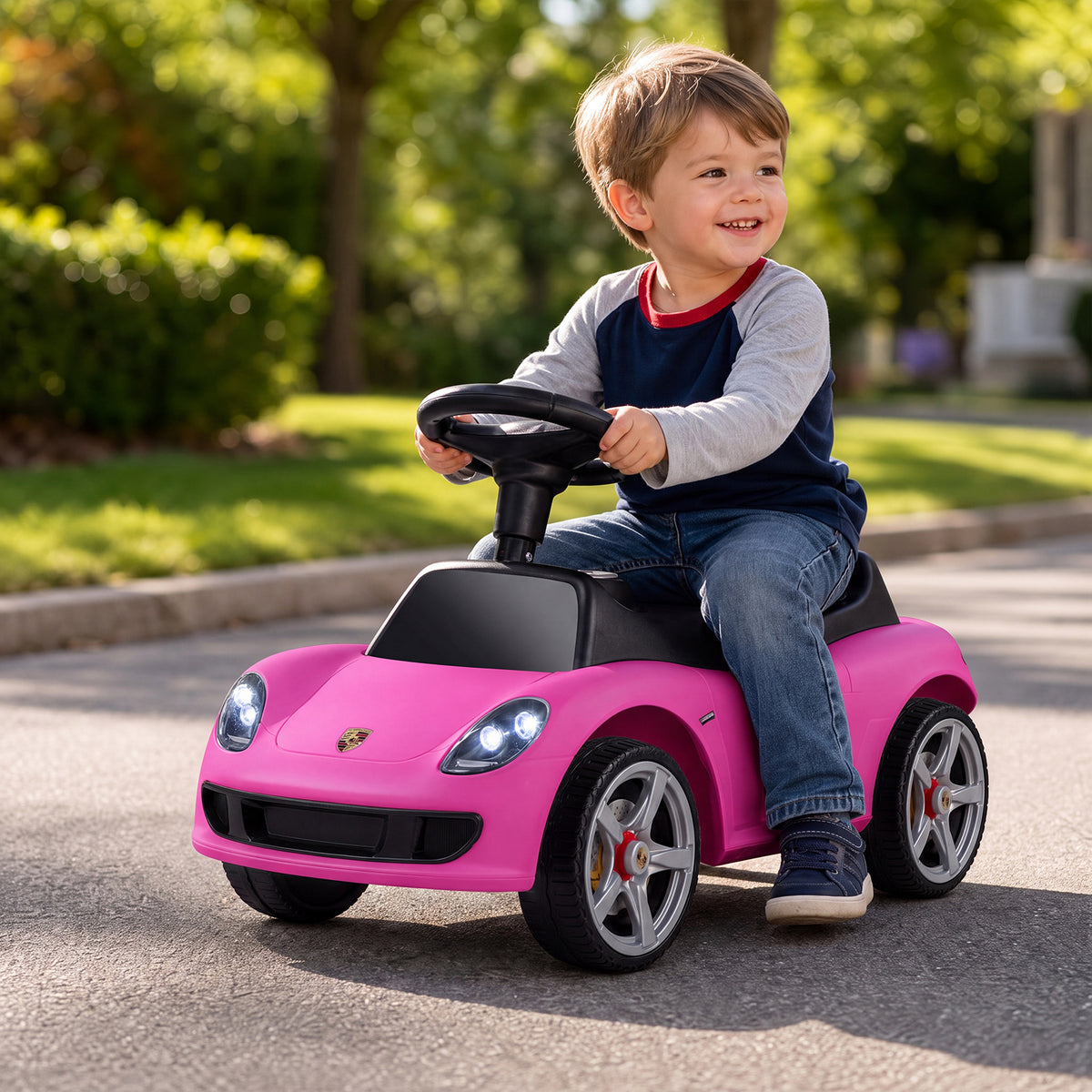 A happy child sitting on the pink sliding car while playing on a sunny street