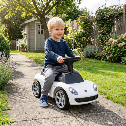The white sliding car being enjoyed by a happy toddler on a garden path