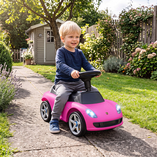 A young boy smiling while riding the pink sliding car on a paved garden path