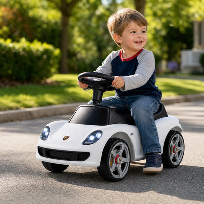 The ride on toy being used by a child on a paved driveway with trees in the background