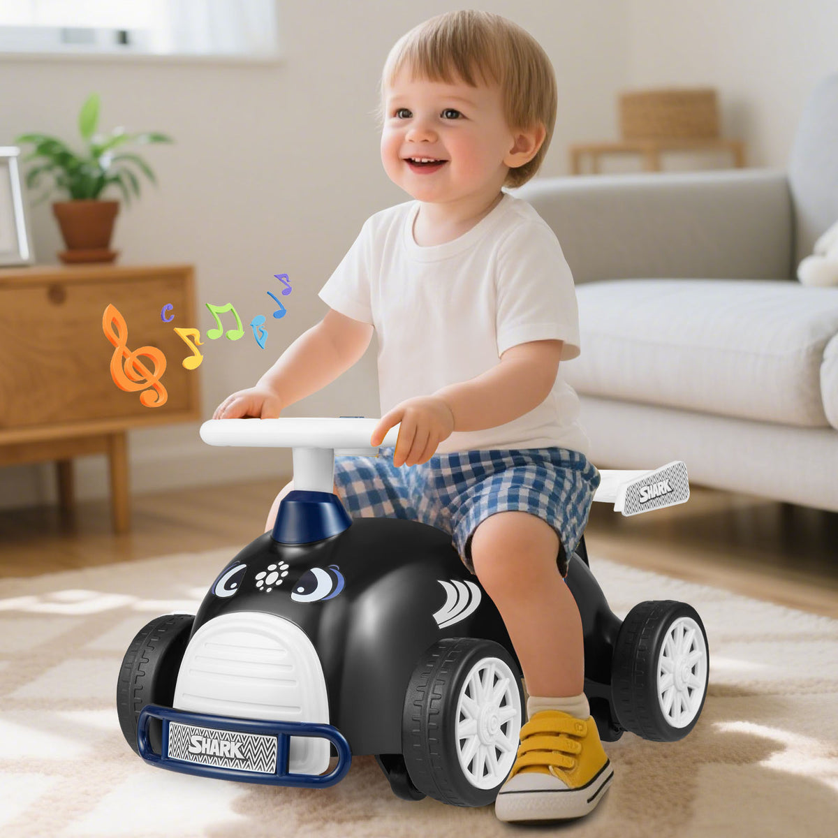 Happy toddler boy sitting on the black and blue sliding toy car indoors with music notes