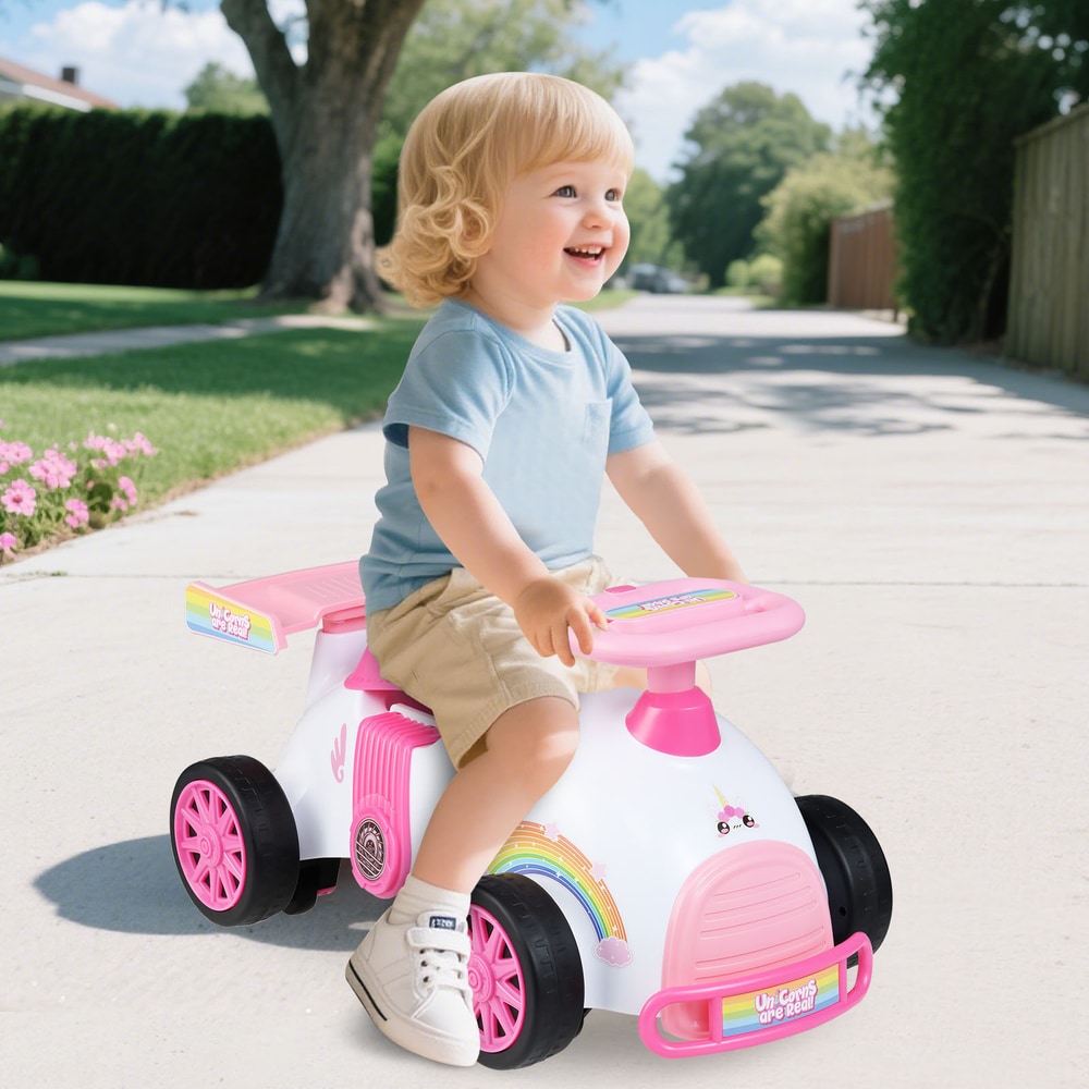 A smiling toddler rides the pink push and pedal ride on toy on a pavement