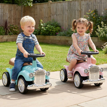 Two children ride on pink and blue vintage cars in a garden