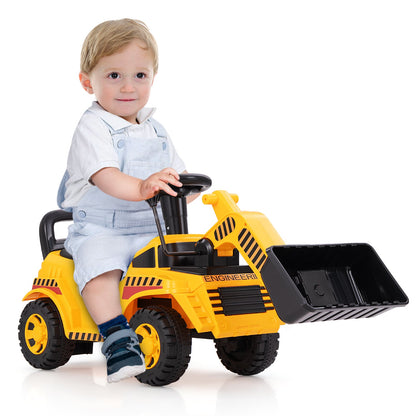 A toddler sits on the yellow ride on digger toy with a black steering wheel and front loader