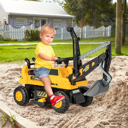 A young child sitting on the yellow kids electric car in a sandy outdoor play area