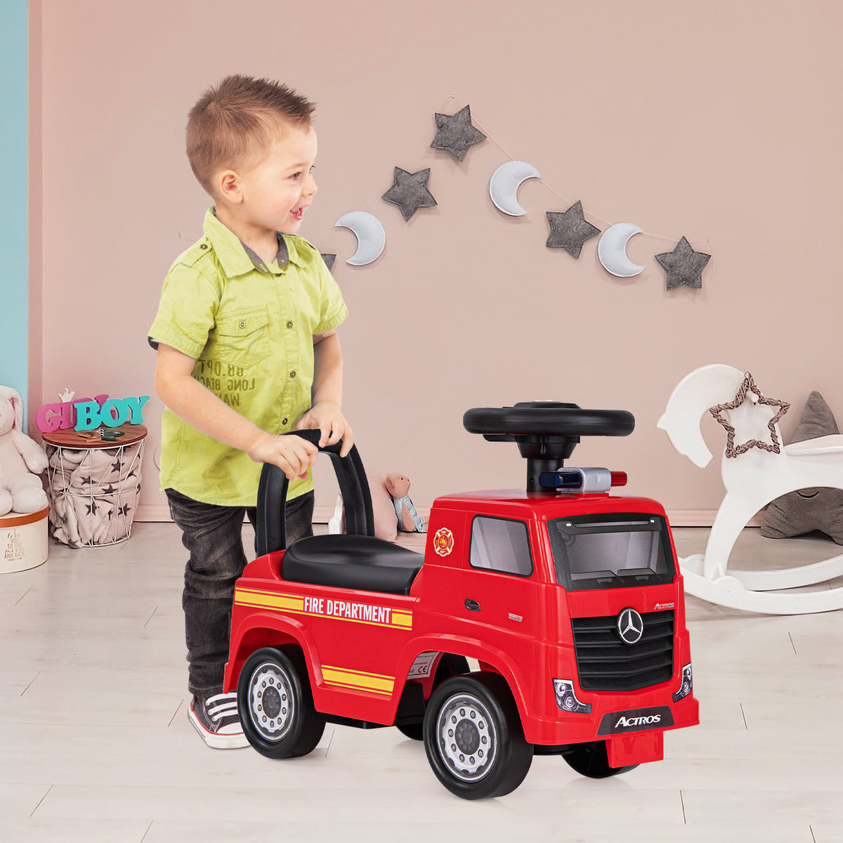 A child pushes the red fire truck toy along a carpeted floor indoors