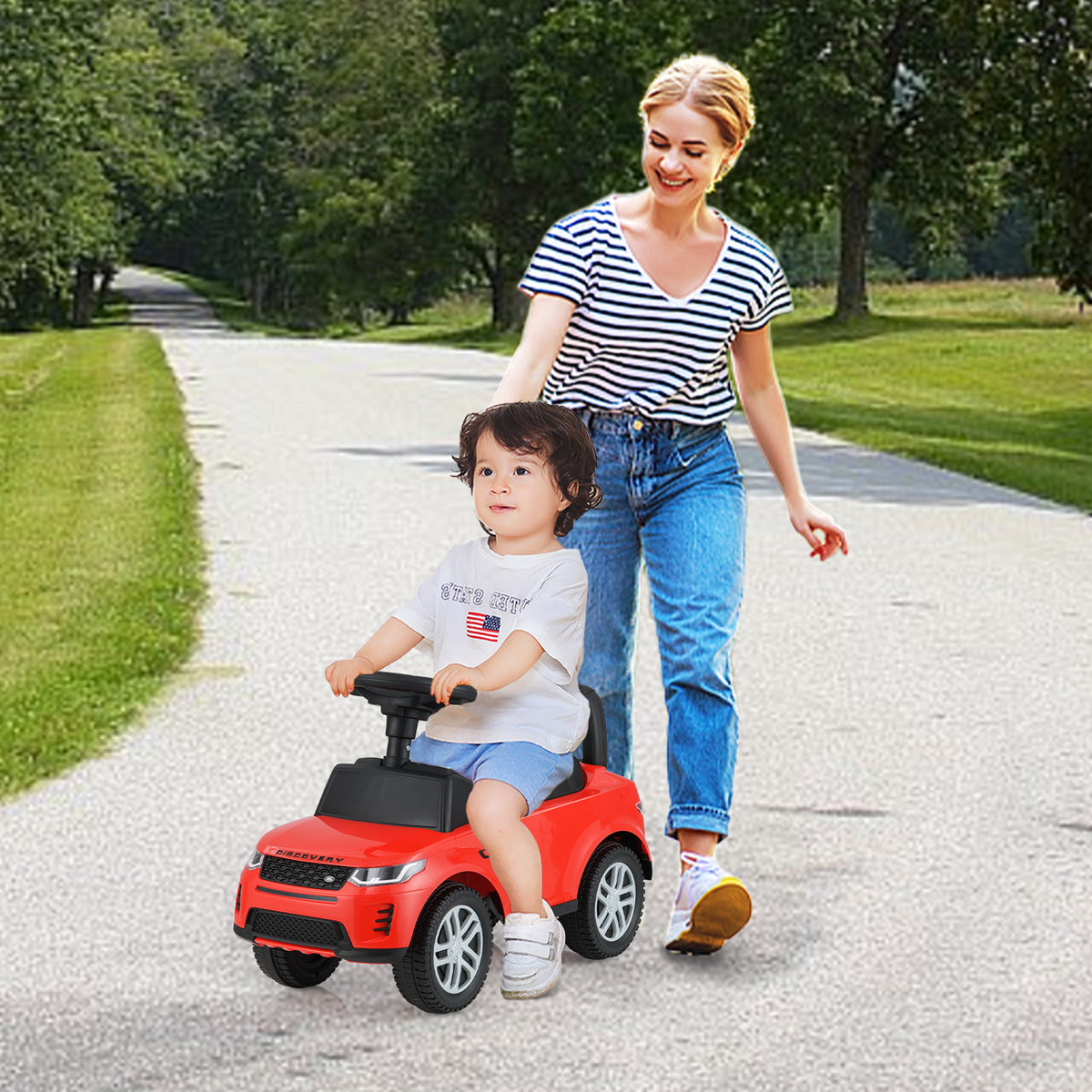 A mother pushes her child on the red ride on push car outdoors
