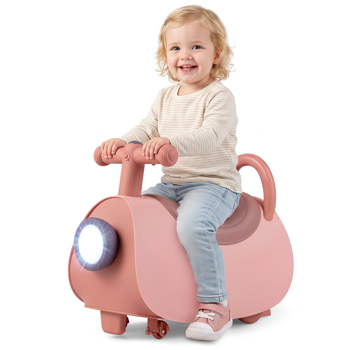 A young child smiles while sitting on the pink push and pedal ride on toy