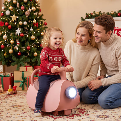 A family smiles as a child rides the pink push and pedal ride on toy at Christmas