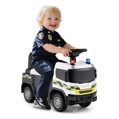 A smiling toddler in a police uniform enjoys riding the push and pedal ride on toy indoors