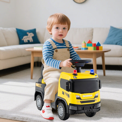 A toddler sits on the yellow push car in a living room setting