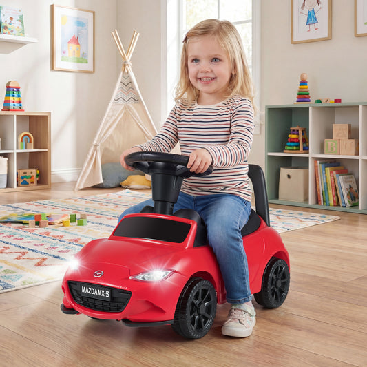 the red Mazda sliding toy with illuminated headlights being used by a toddler indoors