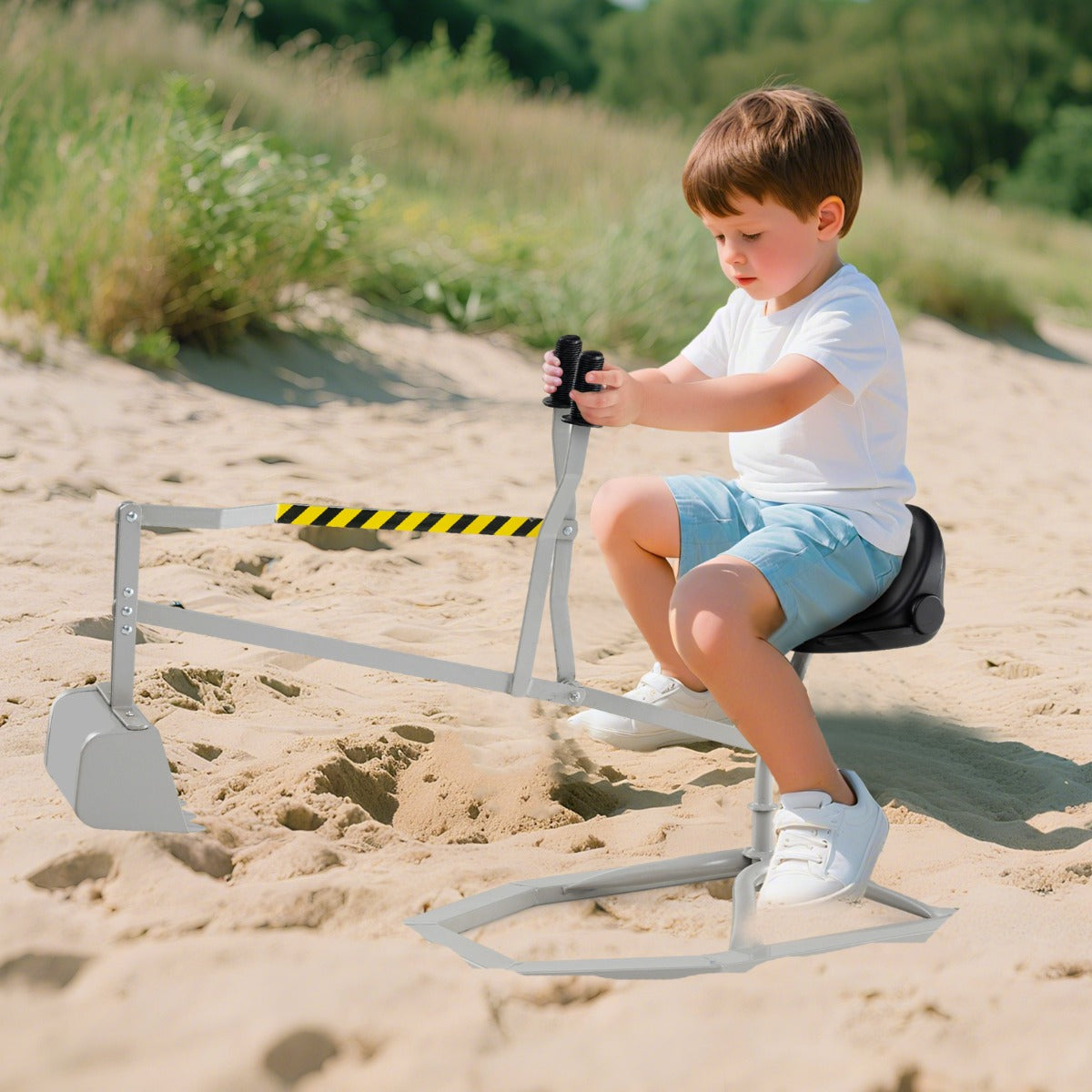 A young boy sitting on the sand digger toy and playing in a sandy outdoor area