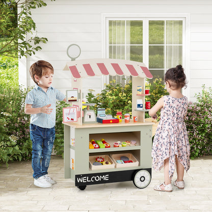 The play kitchen set being used by two children in a garden setting with a white house background