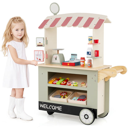 The play kitchen set standing next to a young girl who is interacting with the toy food items