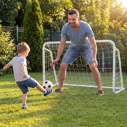 A father and son playing football in a garden with a mini metal goal