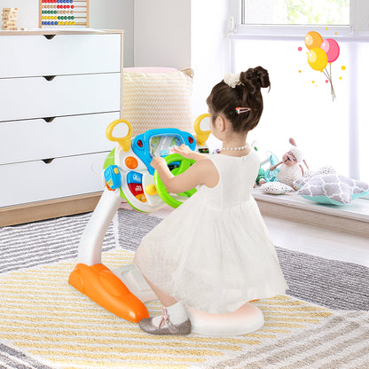 A young girl in a white dress sits at the musical toy steering wheel and stool in a bright room