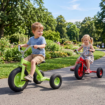Two children riding the green and red kids tricycles in a park