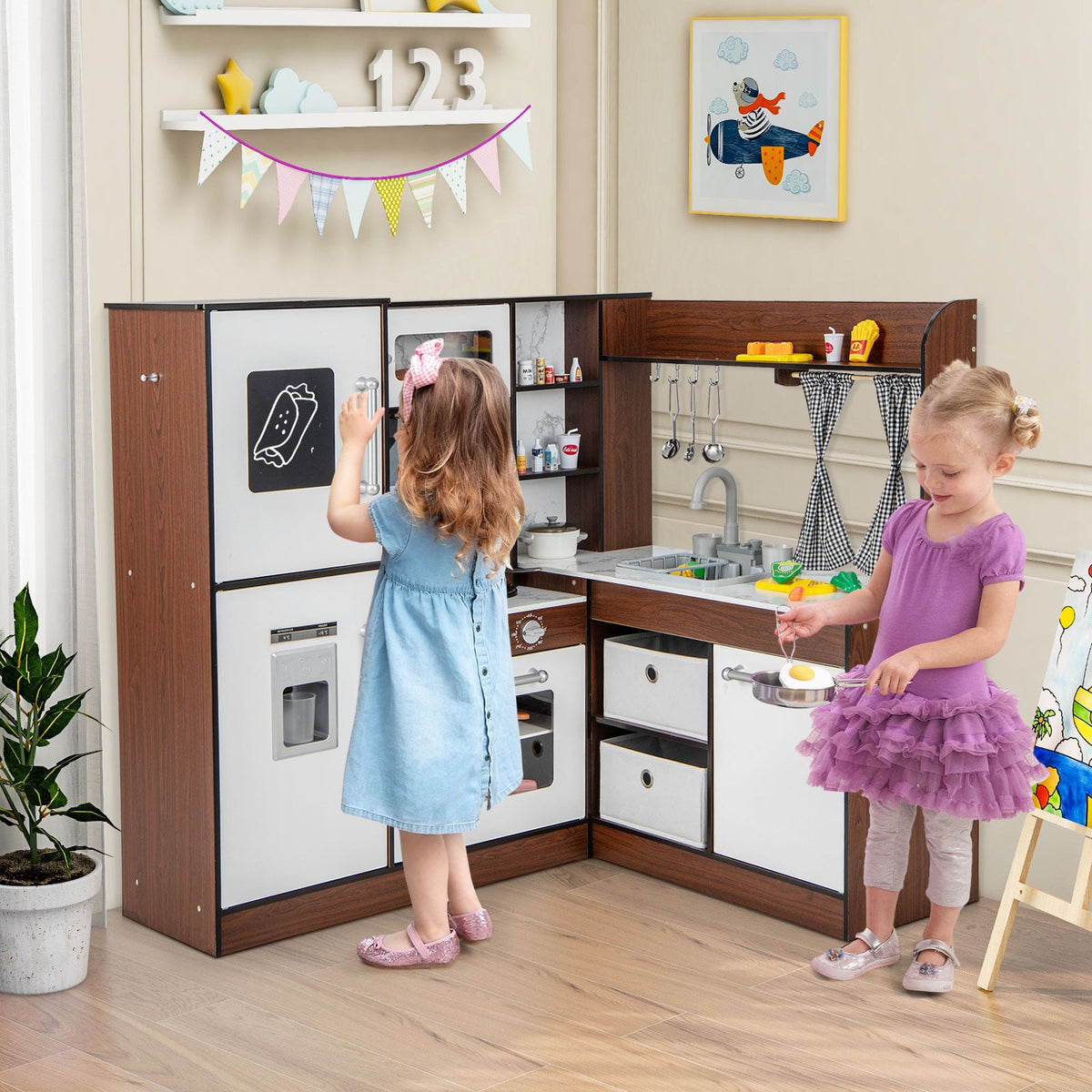 The play kitchen set being used by a young girl in a dress who is pretending to cook food