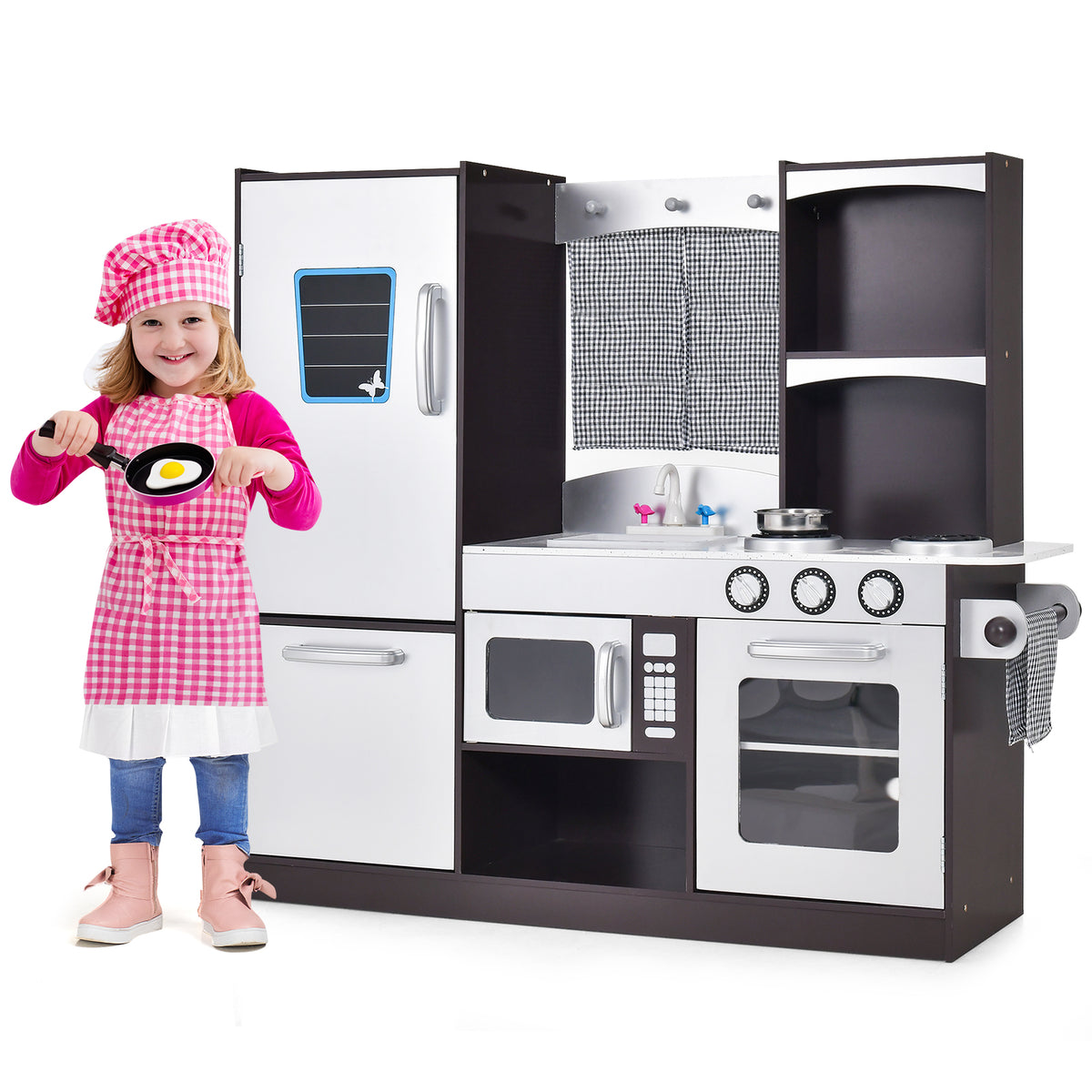 The play kitchen set next to a young girl wearing a pink apron and chef hat holding a toy pan