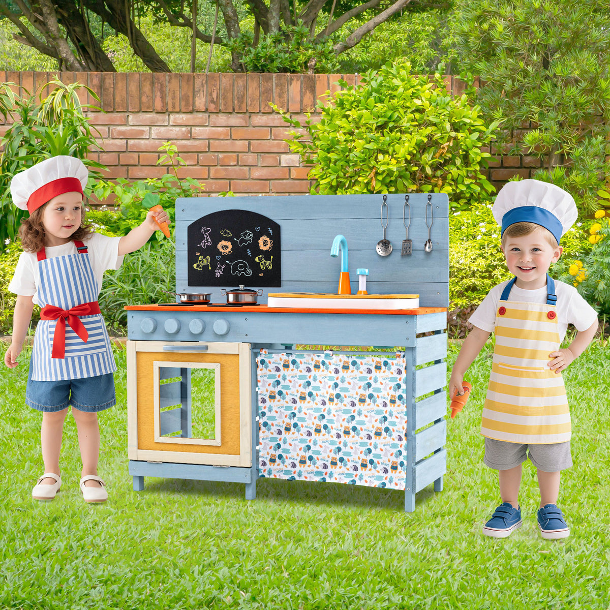 Two children wearing chef hats play with the wooden kitchen set outside