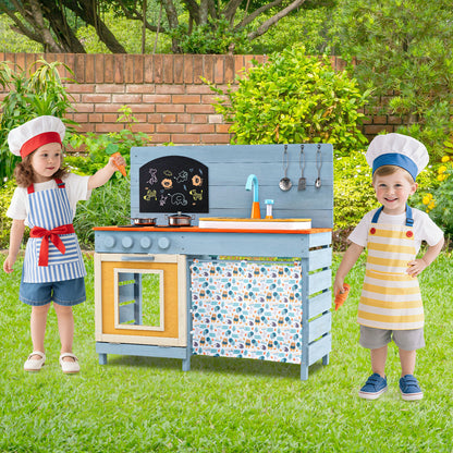 Two children wearing chef hats play with the wooden kitchen set outside