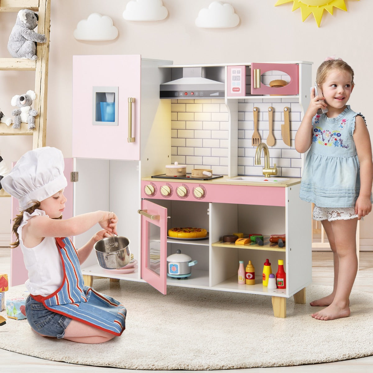 Children playing with the pink play kitchen set, one is cooking and the other is on the phone