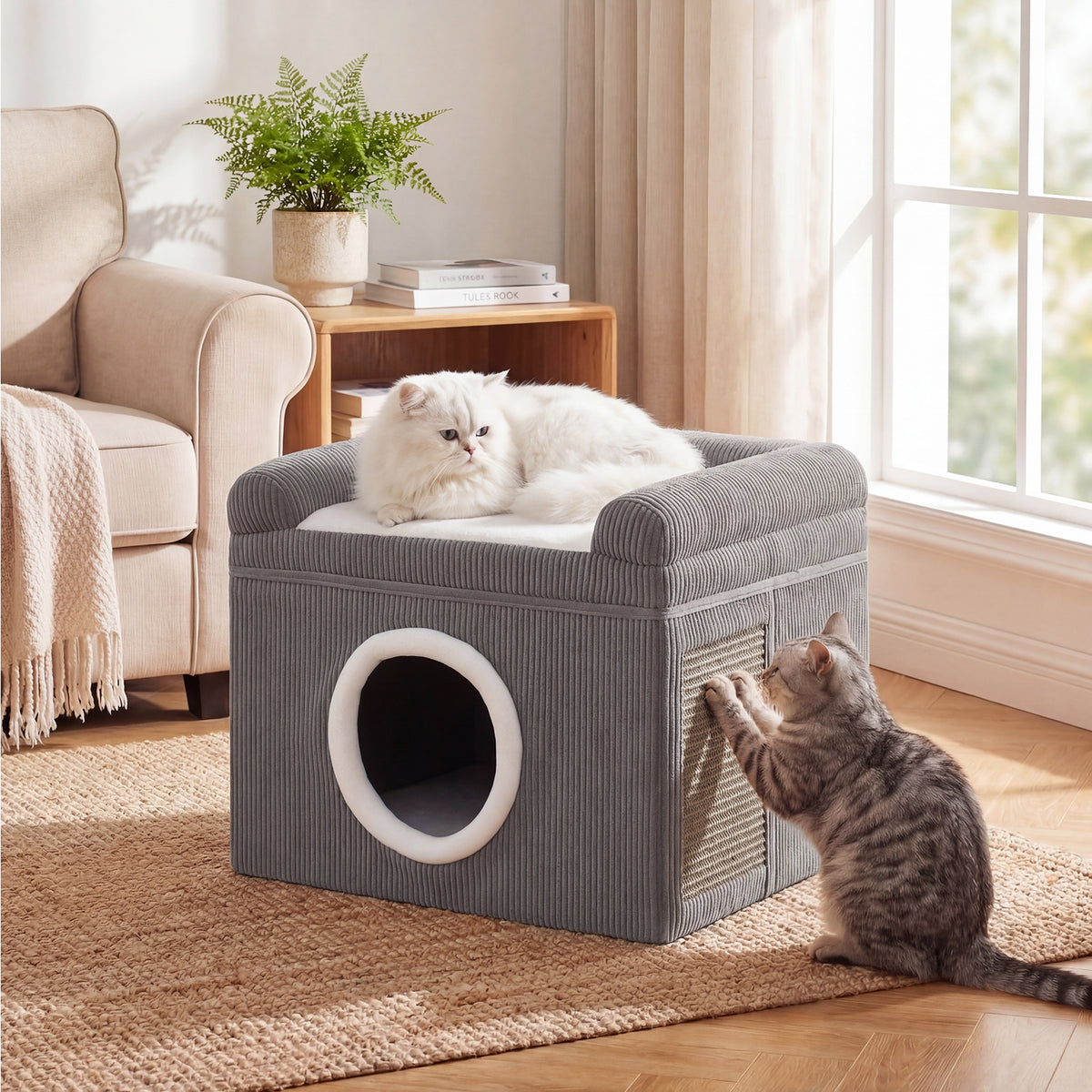 The cat furniture in a living room with one cat resting on top and another scratching the side