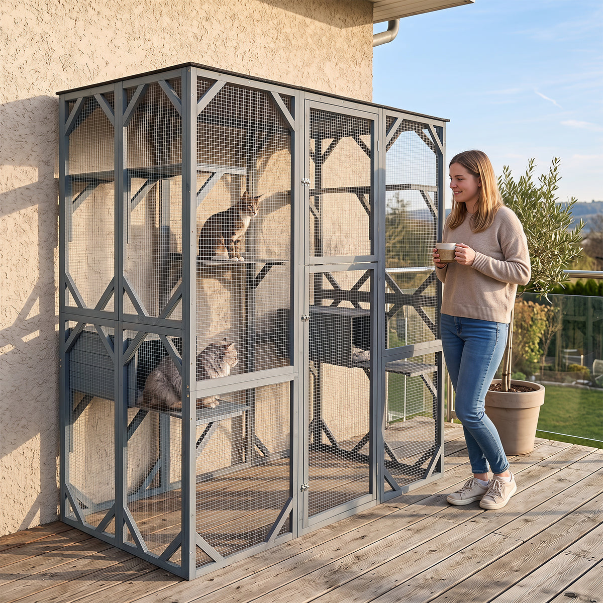 A woman stands on a wooden deck next to the outdoor cat enclosure with cats inside