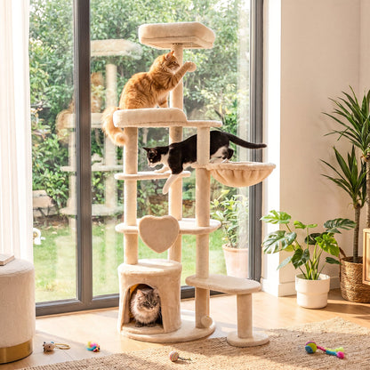 Several cats playing on a large beige multi-level cat tree in a bright room