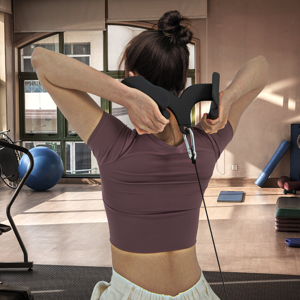 Woman performing a triceps pushdown exercise with a curved bar attachment