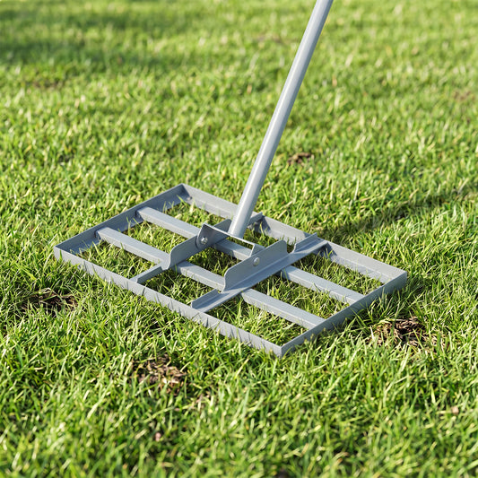 The metal levelling rake head resting on green grass