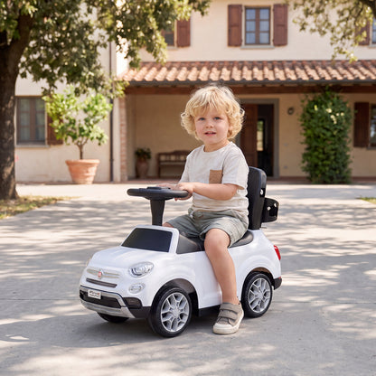 The ride on toy being ridden by a toddler in a courtyard in front of a house