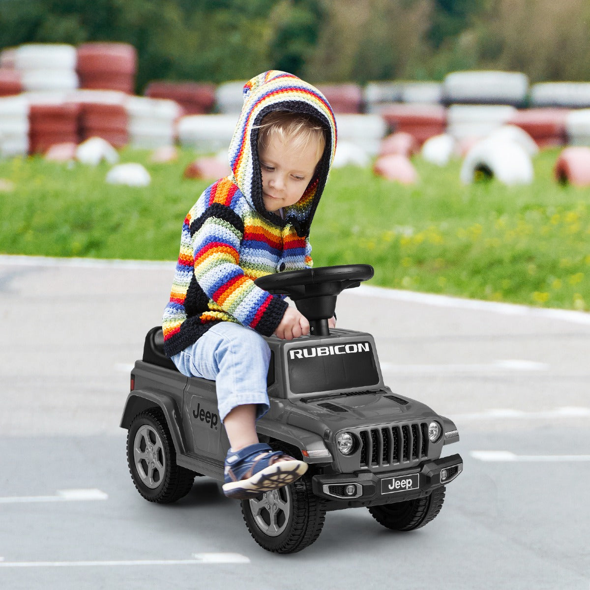 Toddler sitting on the grey Jeep ride on push car outdoors