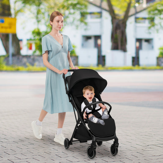 The baby stroller being pushed by a woman on a paved path with a child sitting inside