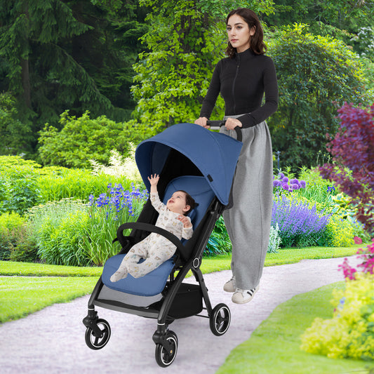 Woman pushing the navy blue baby stroller with a baby inside on a garden path