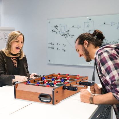 Two adults laughing while playing with the game room table in an office space