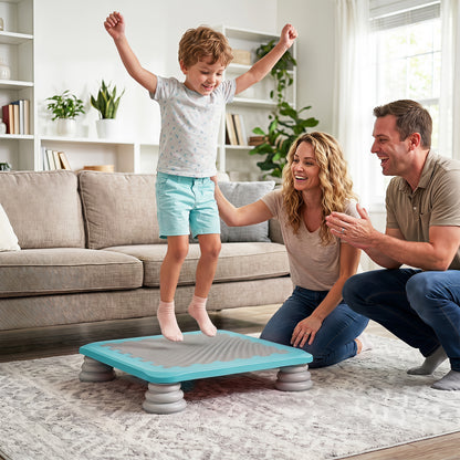 A happy family watches a young boy jump on the blue square trampoline in a living room